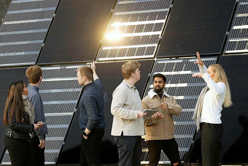 A group of people stand in front of a building with solar panels on the walls. Photo by Geir Mogen/NTNU