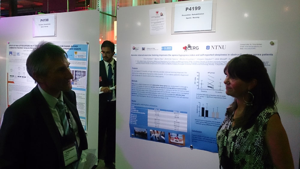Mas talking to woman in front of a poster at a conference