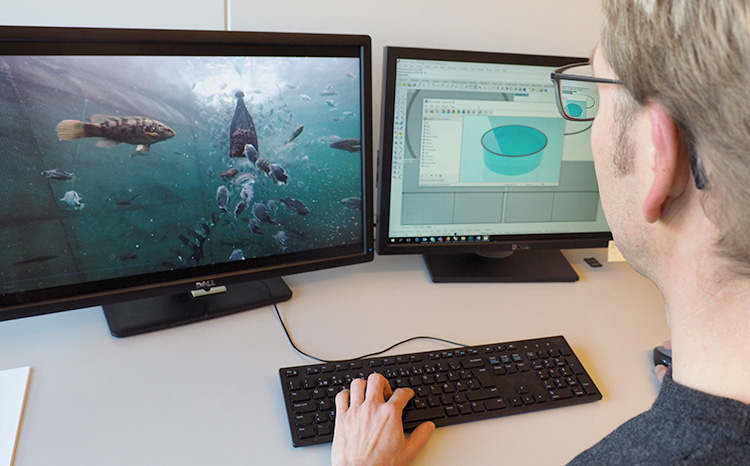 A man watching a computer screen with fish farming