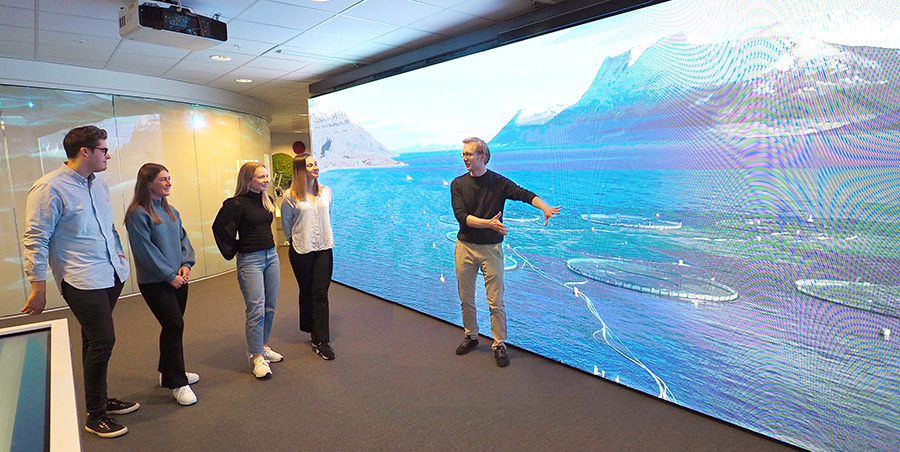 A professor showing students a simulation of salmon farming on a big screen