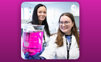 Two women. One of them is showing a bottle with a pink liquid