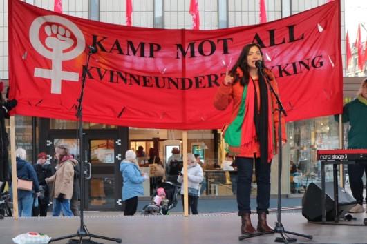 Sonia Ahmadi standing under a red banner on a scene