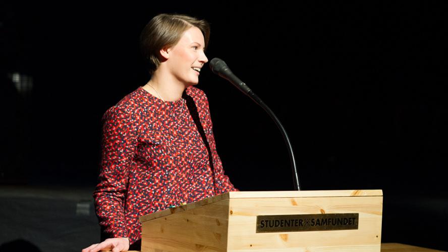 Portrait of Vilde Coward. Credit: Fotogjengen, Studentersamfundet Portrait of female standing talking in a microphone..
