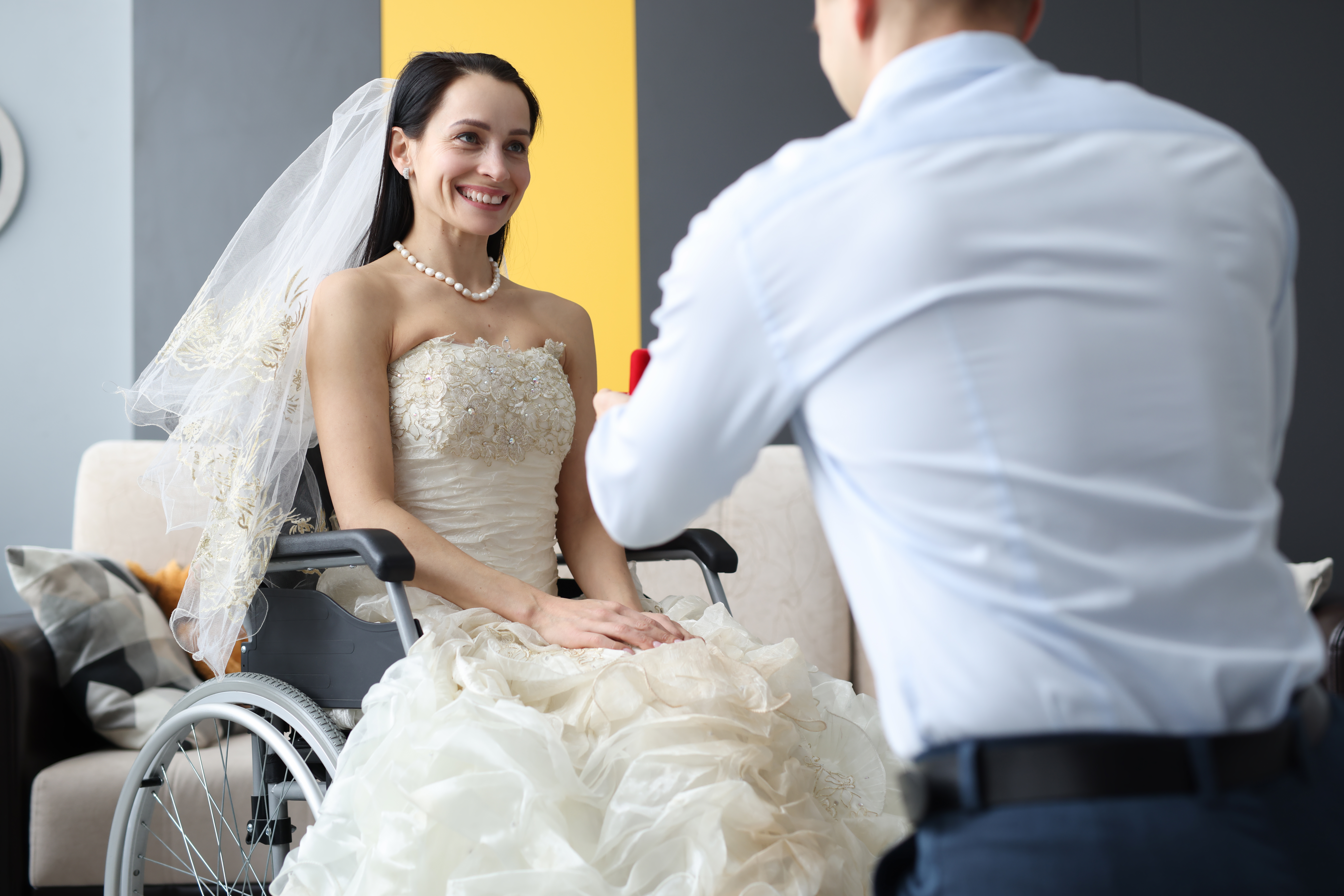 A lady in a bride gown sitting in a wheelchair while being taken picture of. photo.