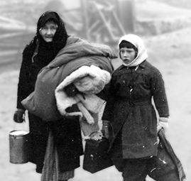 An elderly woman and her granddaughter carrying the possessions they managed to save