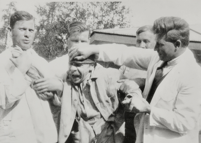 A patient held by staff at a mental institution. Photo