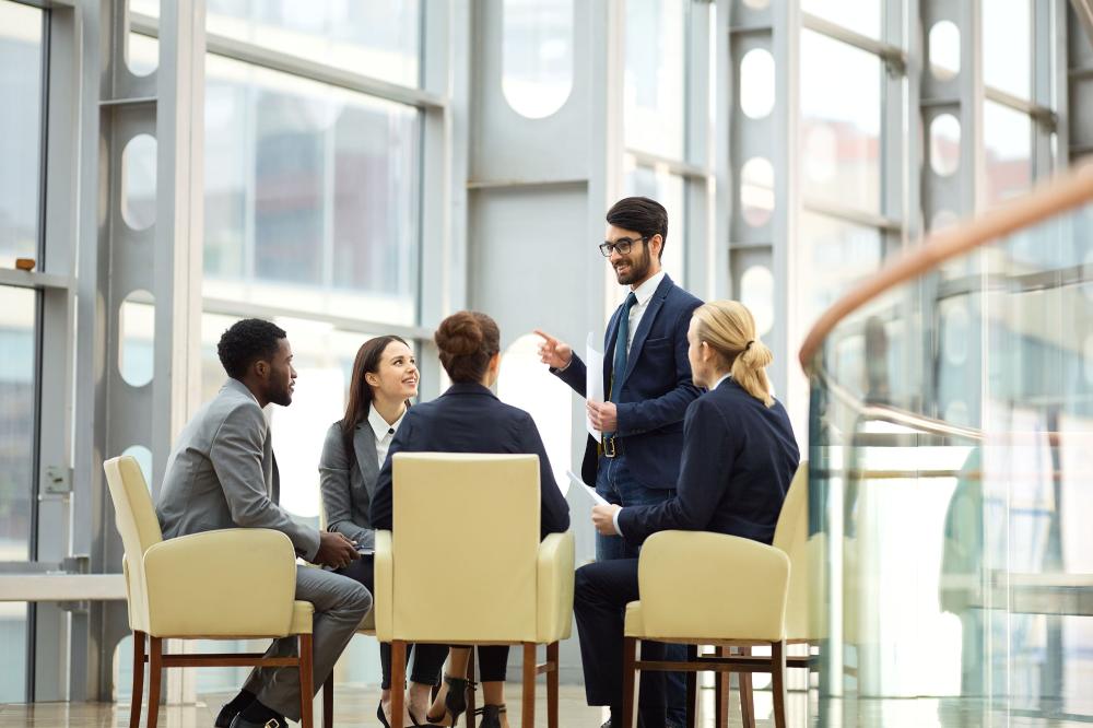 Young businessman answering questions of his colleagues after report