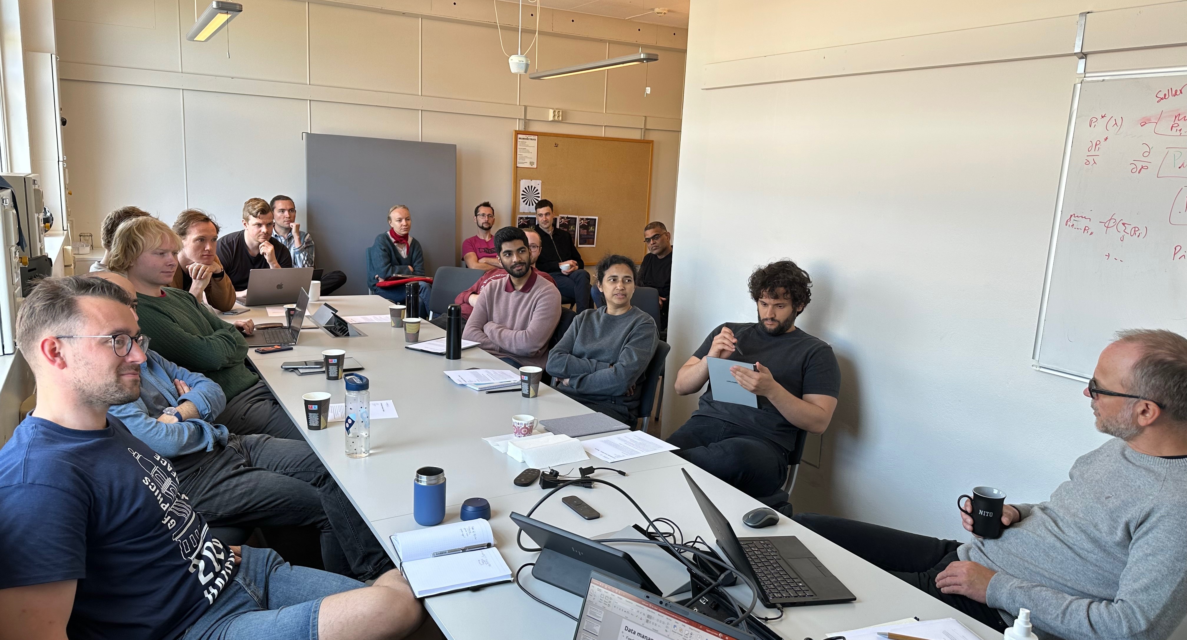 PhDs and postdocs from SFI AutoShips gathered around a conference table, discussing with Innovation manager Kjell Olav Skjølsvik.