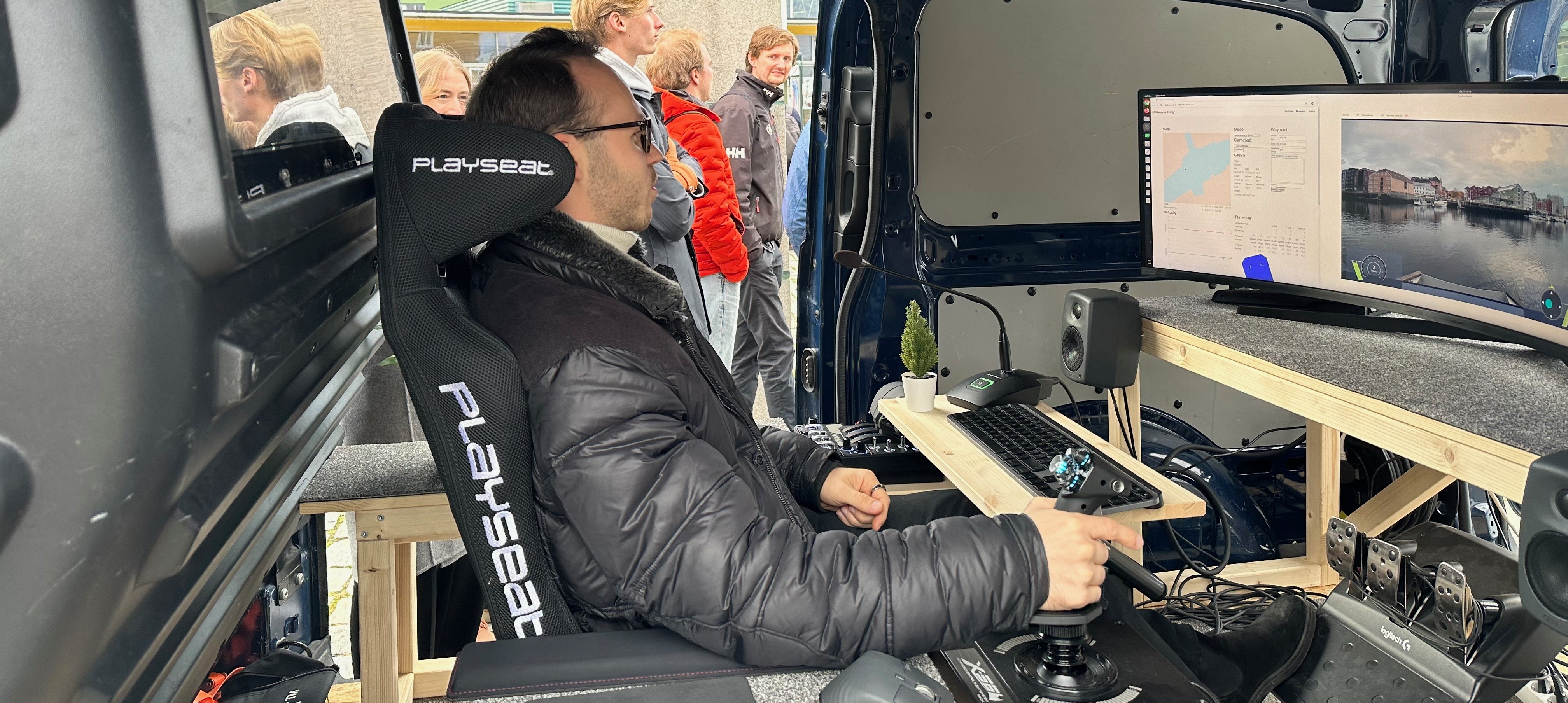 Alexey Gusev, researcher from the adjacent Autoteaming project, remotely controls the ferries milliAmpere 1 and milliAmpere2, from a mobile operation centre in a parked van at Ravnkloa. The participants at the SFI AutoShip days views the operation.