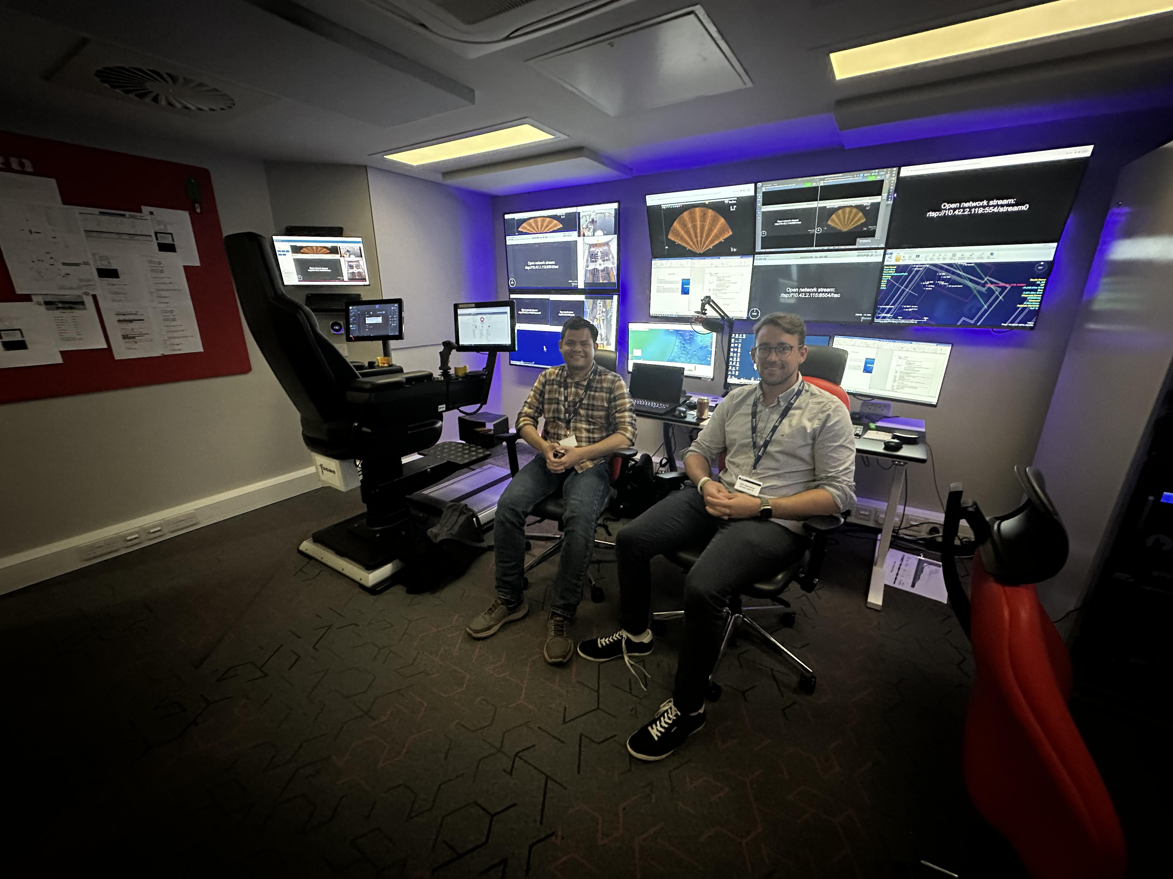 Taufik Akbar Sitompul and Felix-Marcel Petermann, SFI AutoShip researchers, visiting a remote operation centre at Fugro in Aberdeen, sitting in front of the screens and controls.