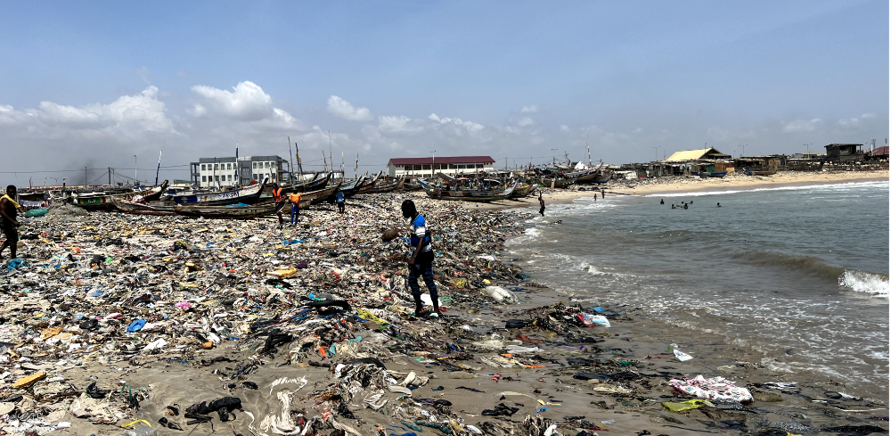 a man walking on a polluted beach in tanzania