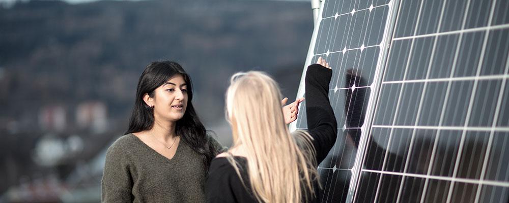 Two students in front of solar panels. Photo: Geir Mogen/NTNU