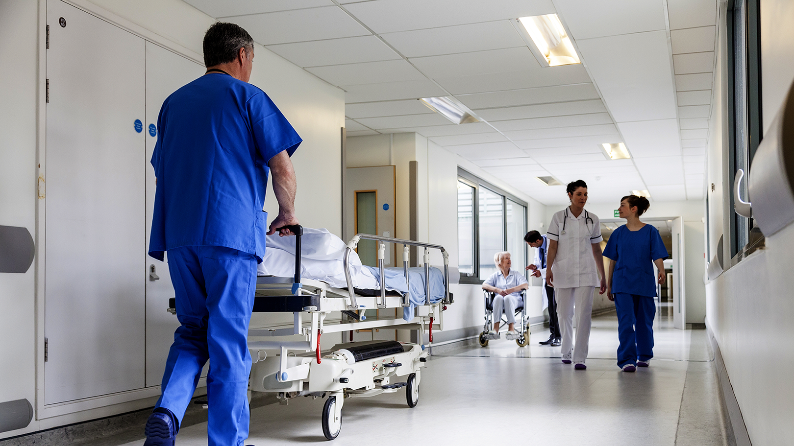 Hospital employee rolling a bed. Photo: Shutterstock