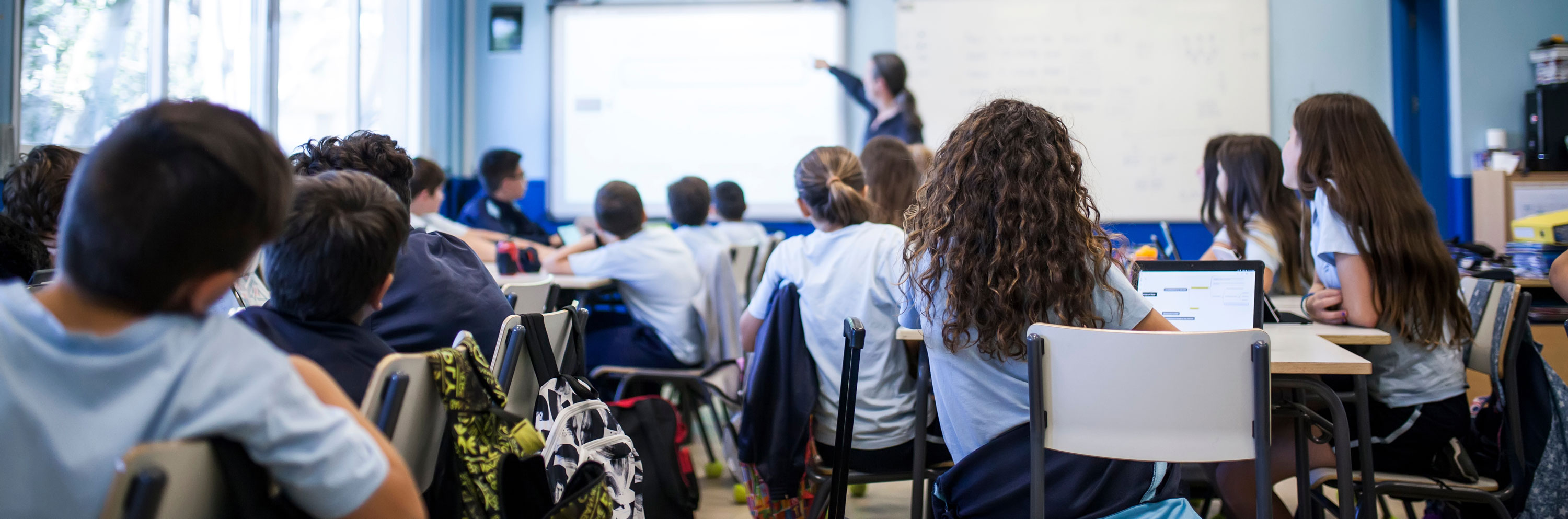 Photo of students in a classroom with a teacher in front.