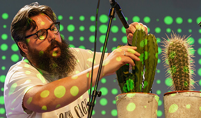 A photo of a man placing microphones close to a cactus.