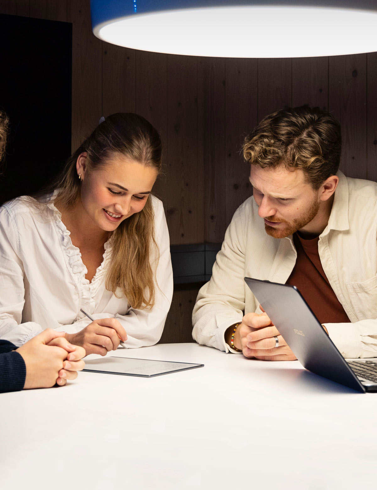 Two students by a table looking at a tablet