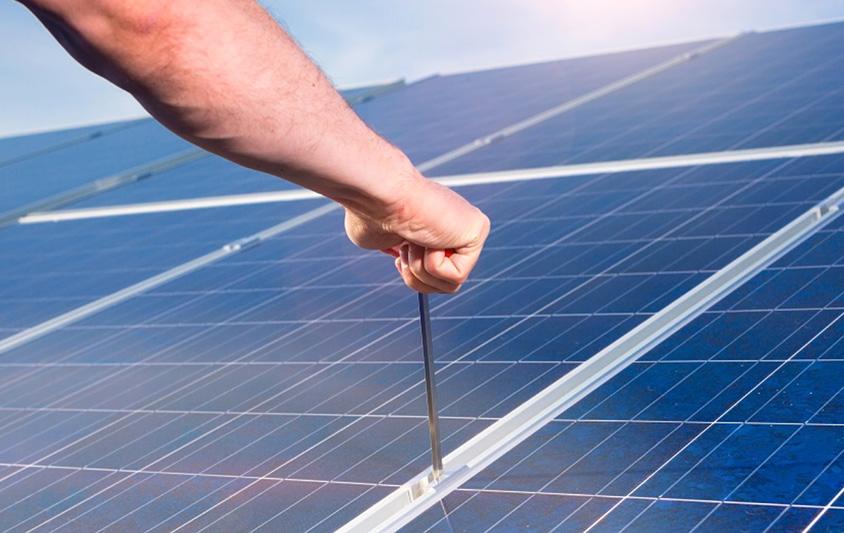 A man holding a tool on a solar panel. Photo