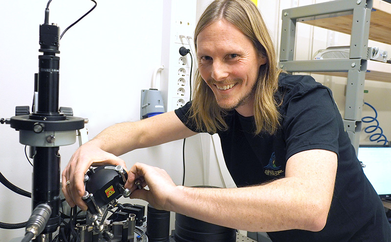 A male researcher looking into the camera while fixing equipment