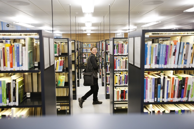 Walking amon the book shelves in the library. Illustration picture.