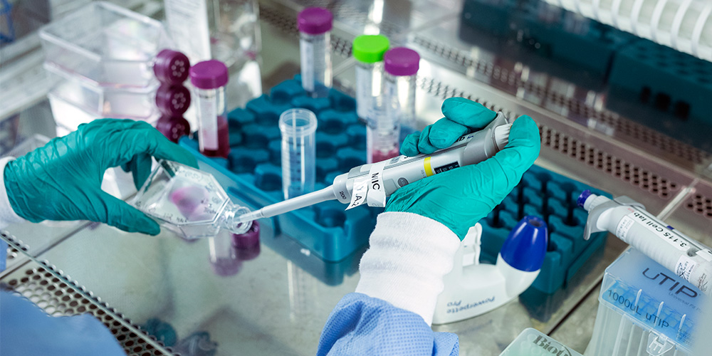 Student holding a pipette and a glass for collecting samples. Photo.